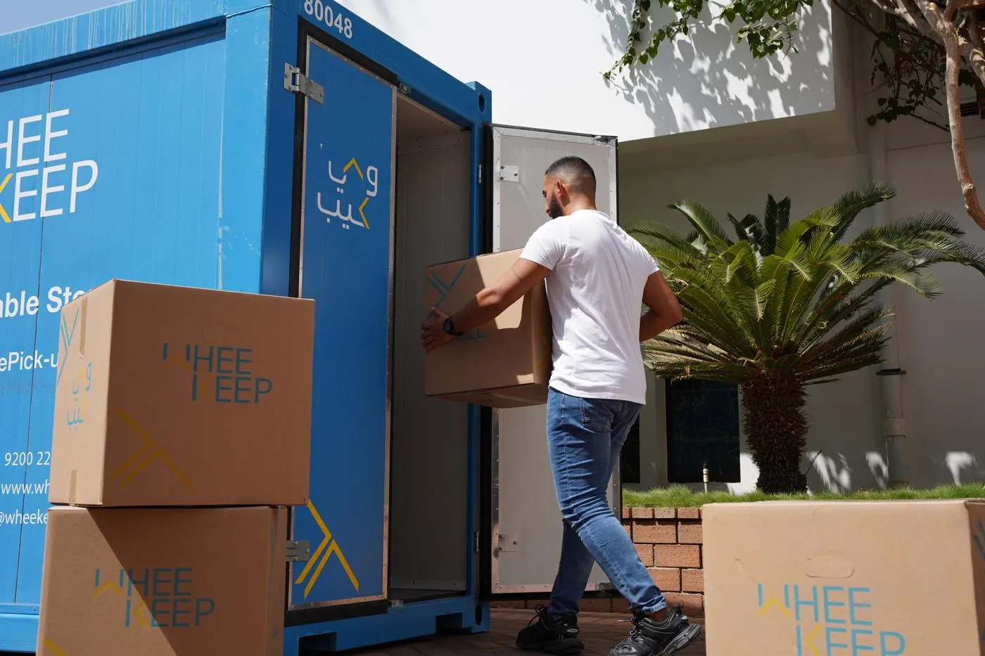 موظف من وي كيب يحمل كرتون عليه الشعار إلى وحدة تخزين أمام بيت