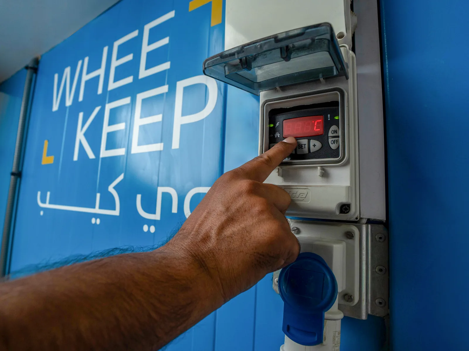 A hand adjusting the temperature control panel on an air-conditioned storage unit